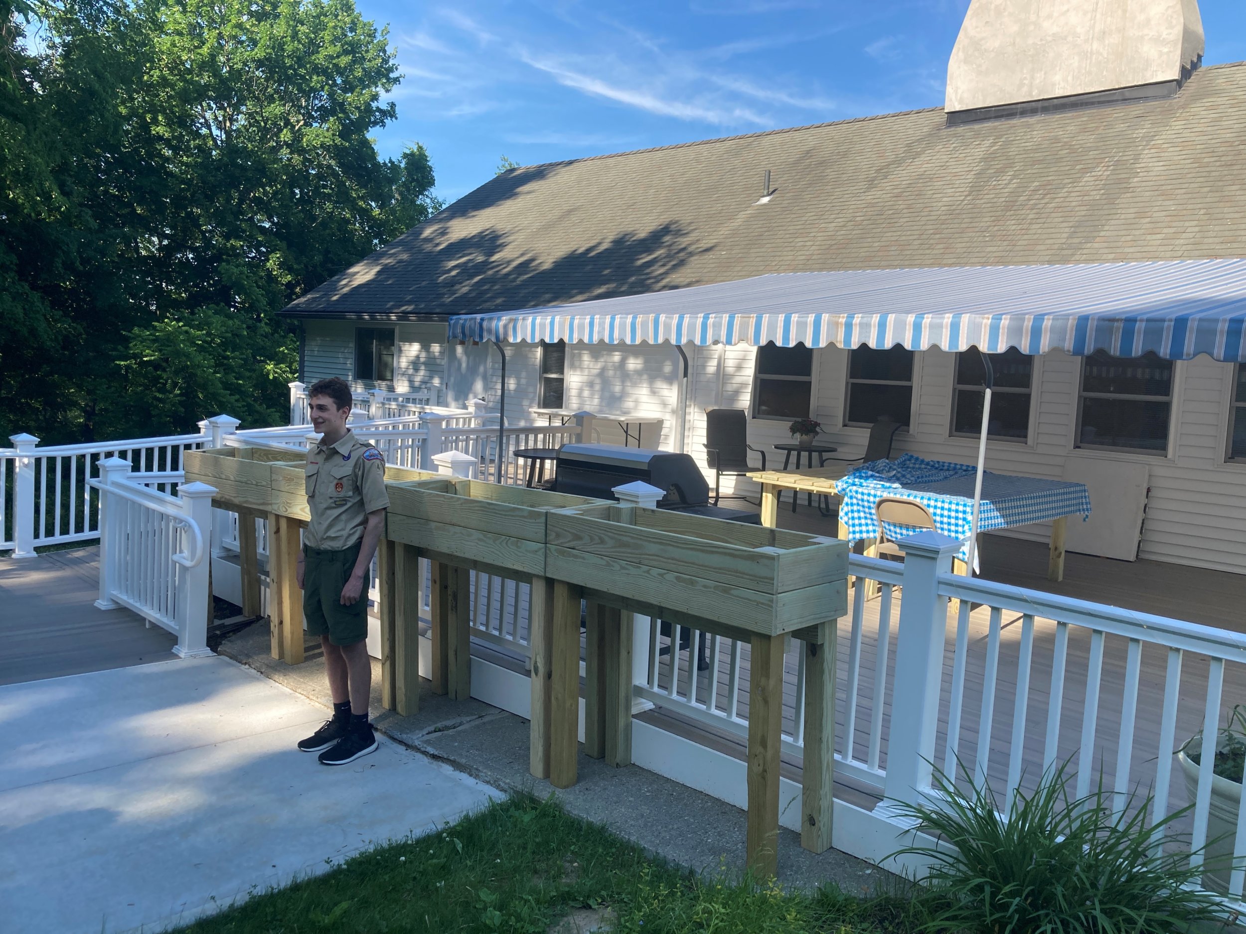 Eagle Scout Ben standing in front of wooden planters that he made|