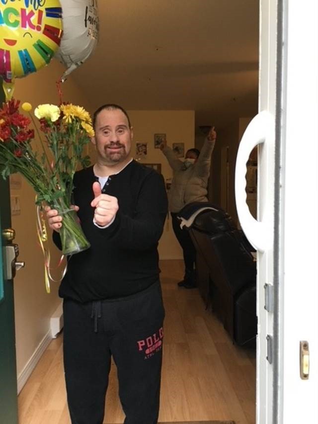 man holding flowers and balloons standing in doorway